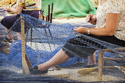 Mujeres obreros trabajando reparando redes de pesca en un puerto